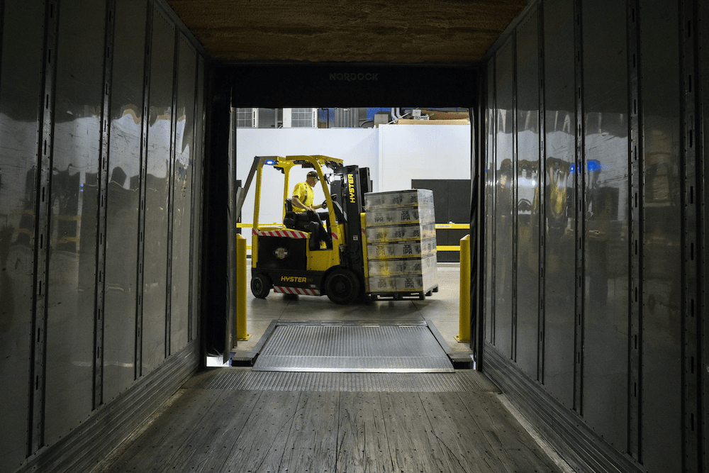 Forklift driving unloading beer cases off transport truck